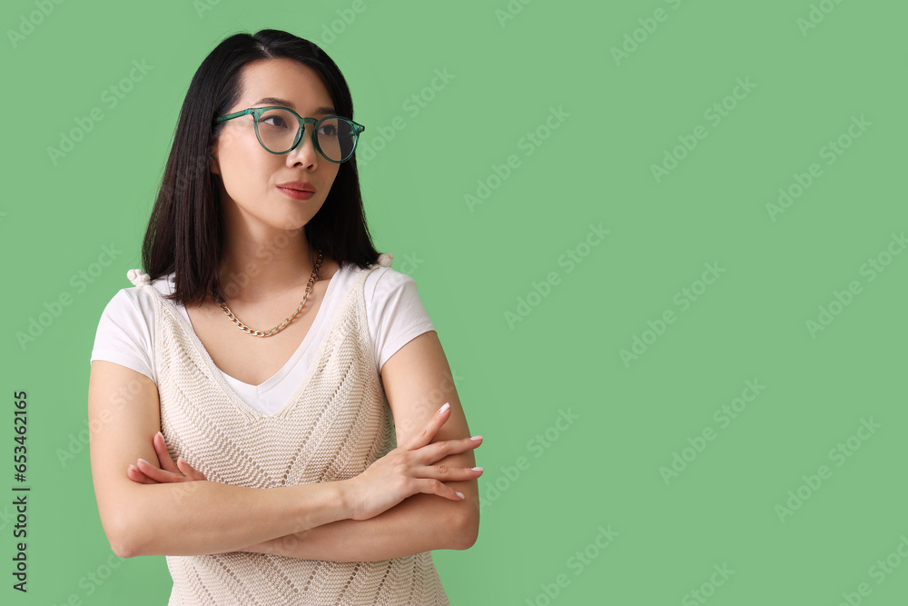 Beautiful Asian woman in stylish eyeglasses on green background