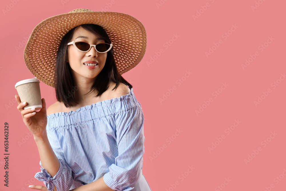 Beautiful Asian woman in stylish sunglasses with cup of coffee on pink background