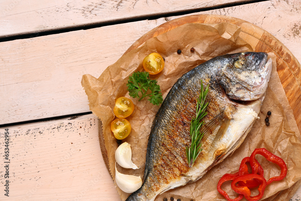 Board with tasty grilled dorado fish on light wooden background