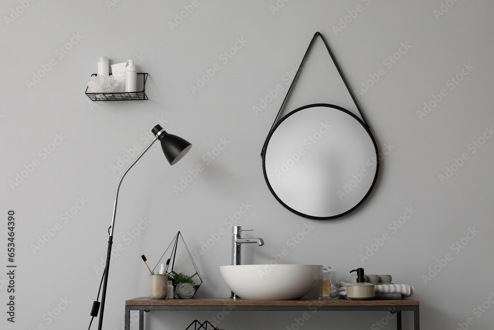 Table with sink bowl, bath accessories and mirror in bathroom