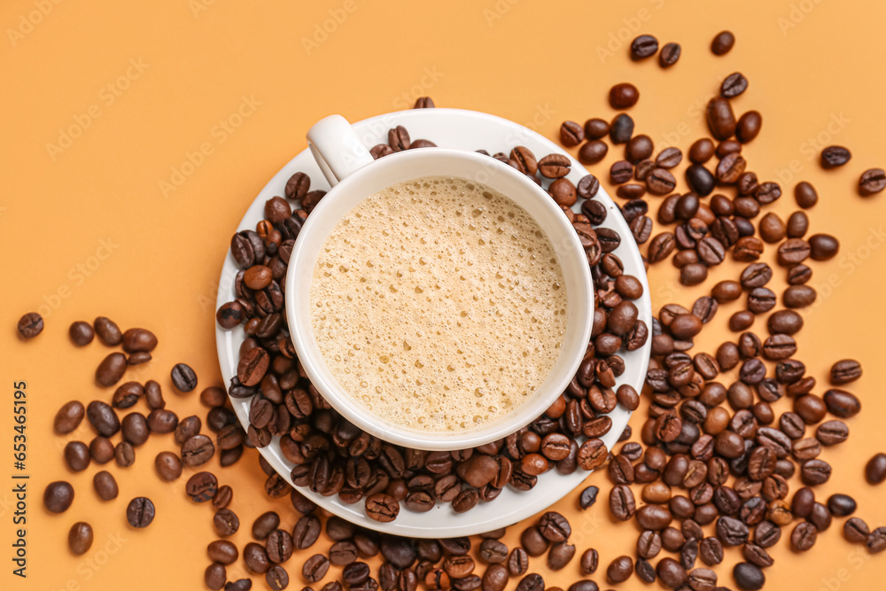 Cup of hot espresso and coffee beans on orange background