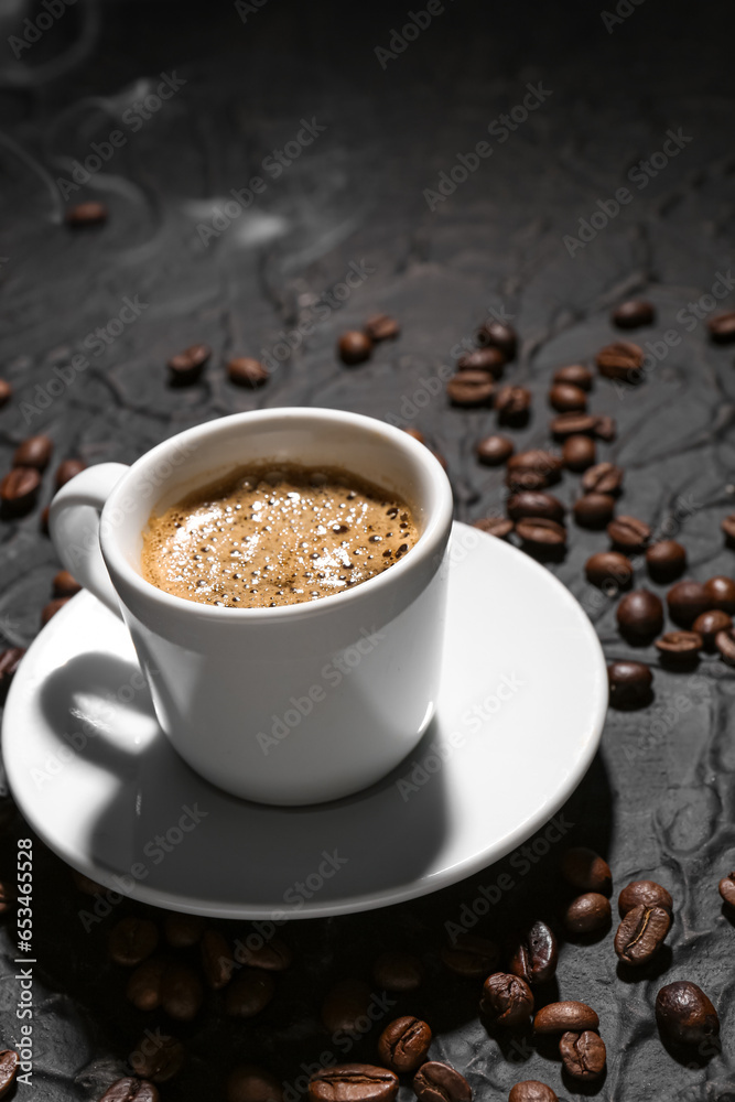 Cup of hot espresso and coffee beans on black background