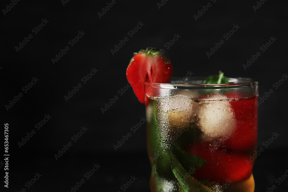 Glass of ice tea with strawberry and mint on black background