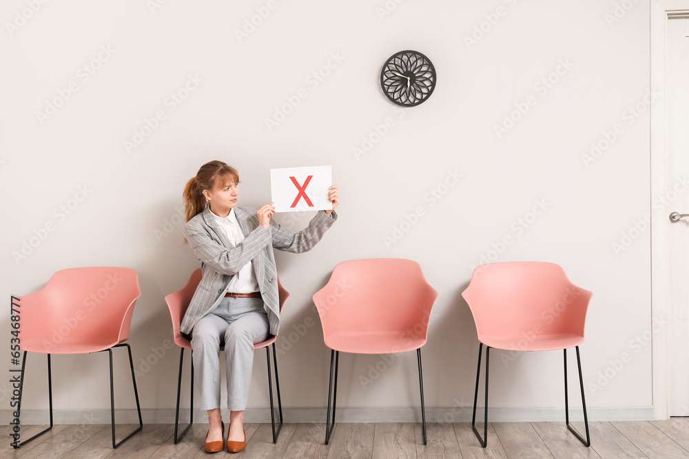 Female applicant holding paper sheet with cross in room