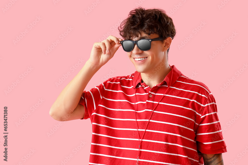 Male lifeguard in sunglasses on pink background