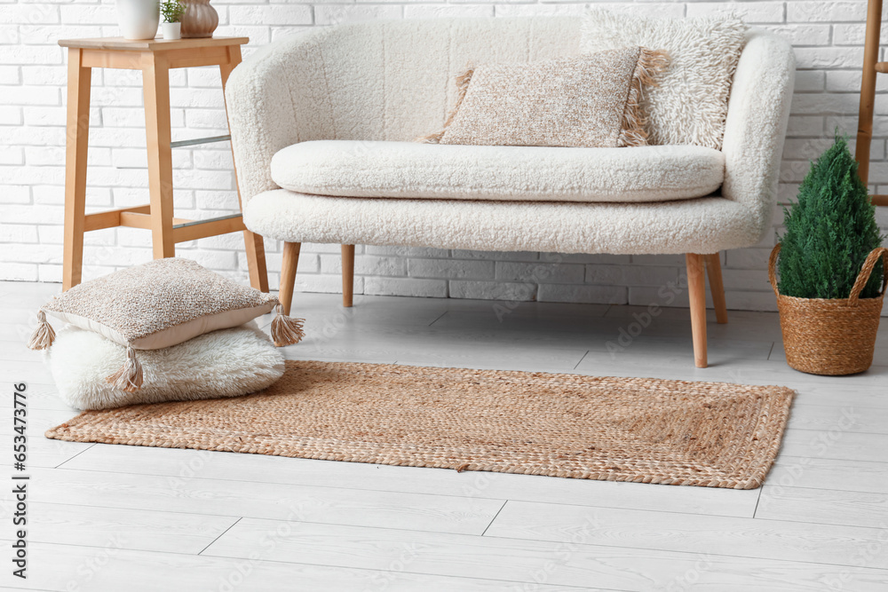 Interior of light living room with white sofa and wicker carpet