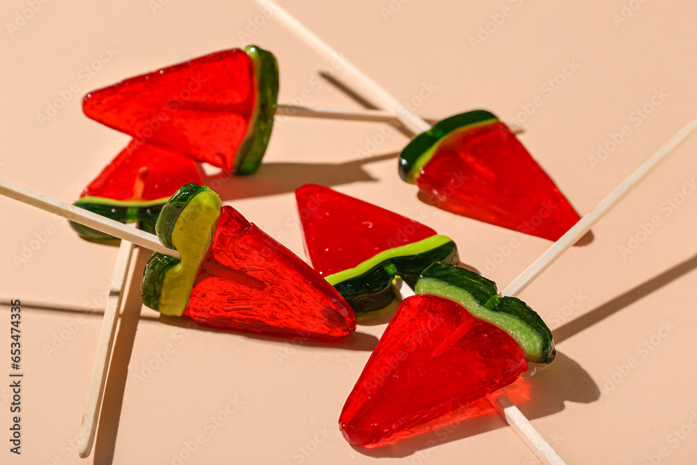 Lollipops in shape of watermelon slice on beige background