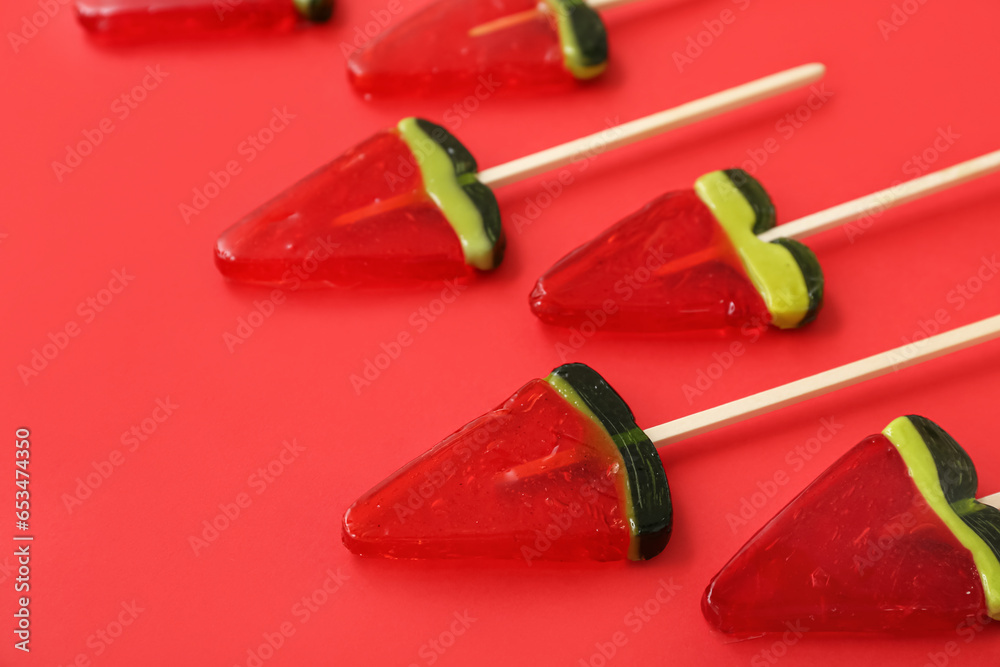 Lollipops in shape of watermelon slice on red background