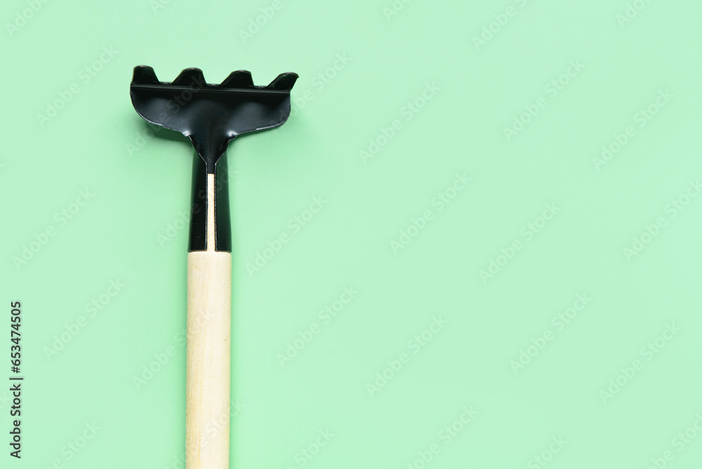 Gardening rake on green background