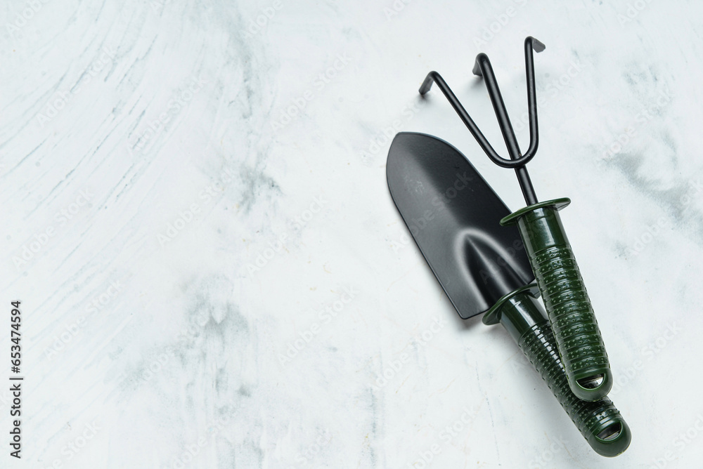 Gardening rake and shovel on white marble background