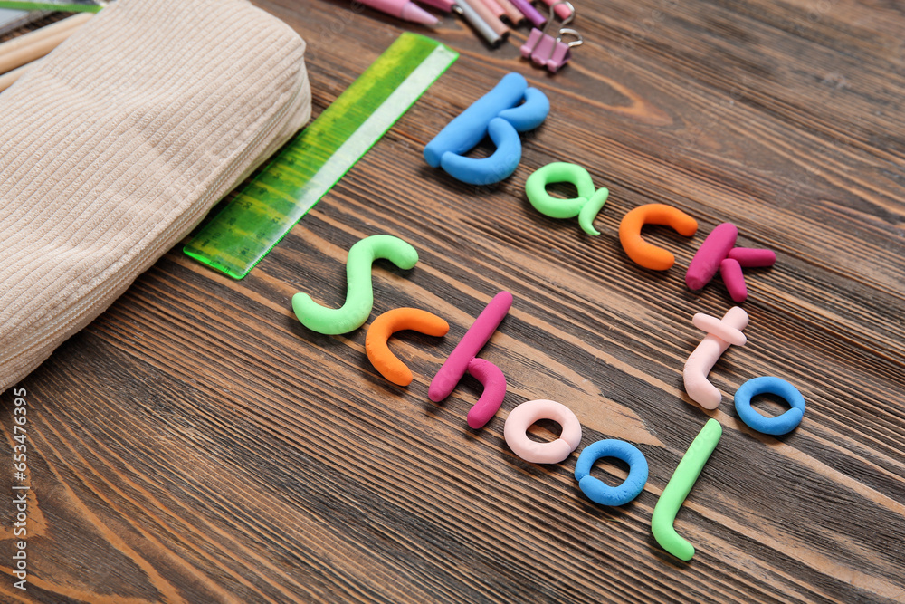 Text BACK TO SCHOOL and stationery on wooden background