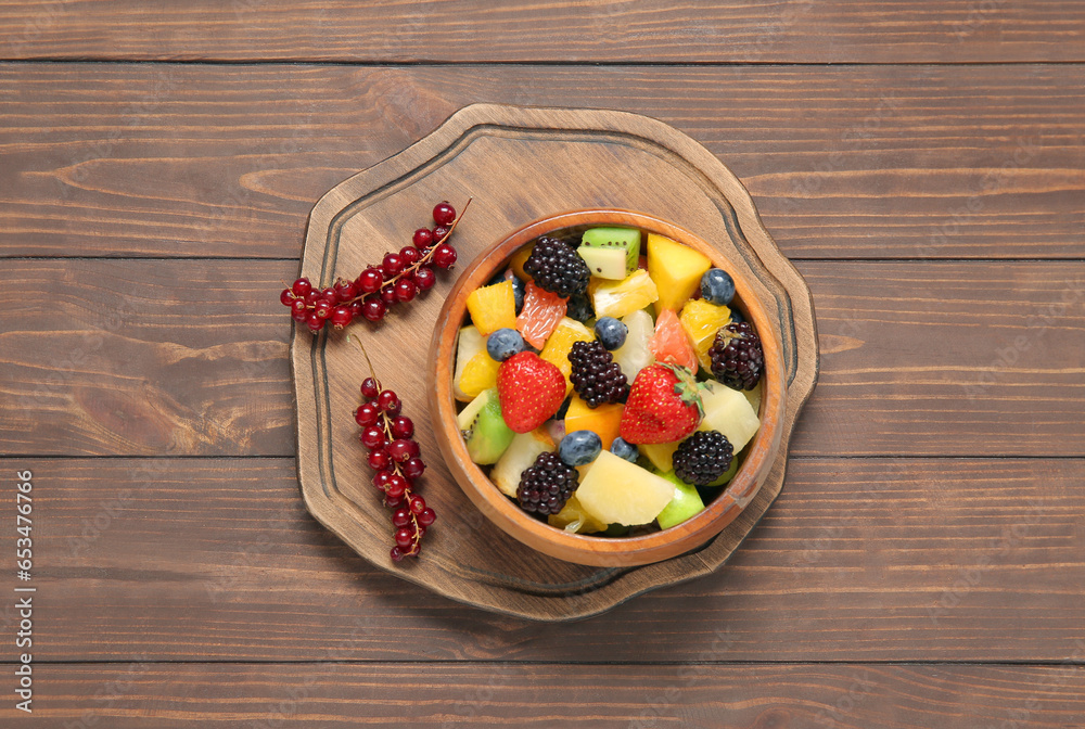 Bowl of fresh fruit salad on wooden background