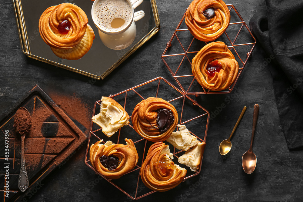 Tasty cruffins and cup of coffee on black background