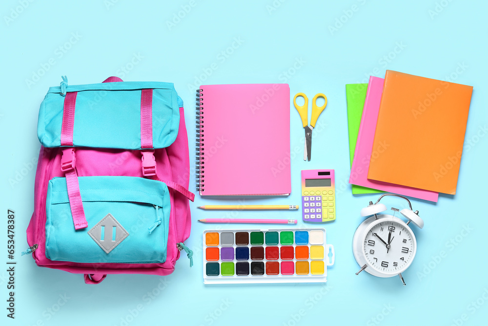 Stylish school backpack with different stationery on blue background