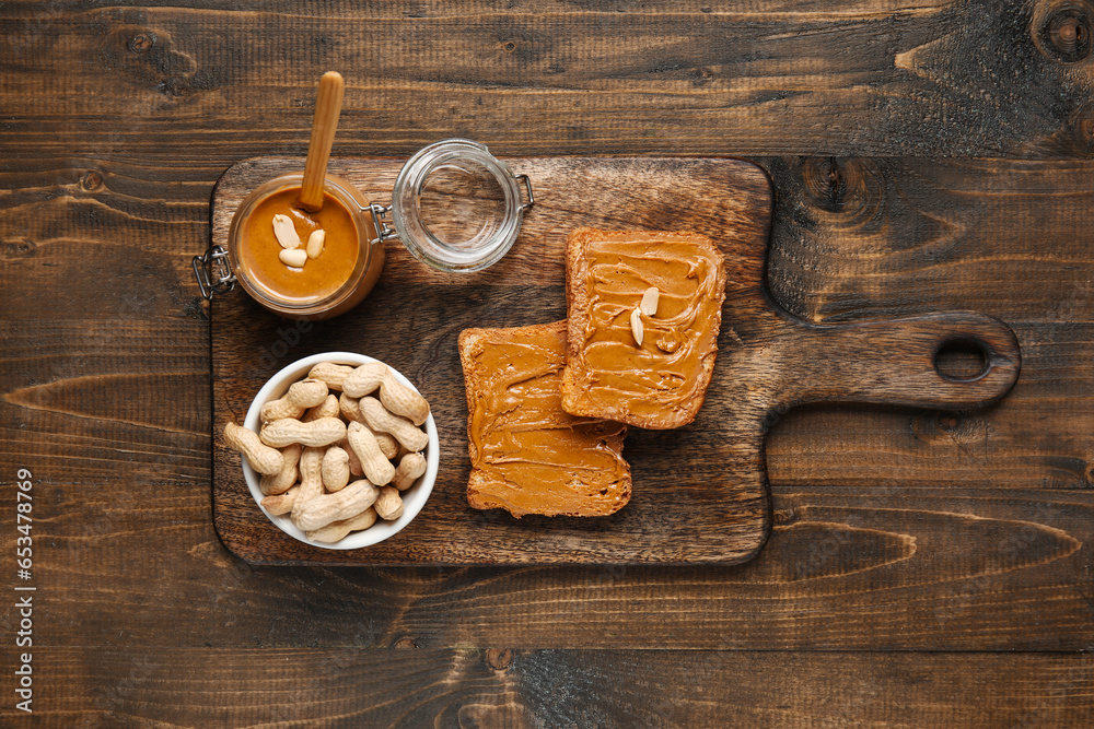 Board of toasts with peanut butter and nuts on wooden background