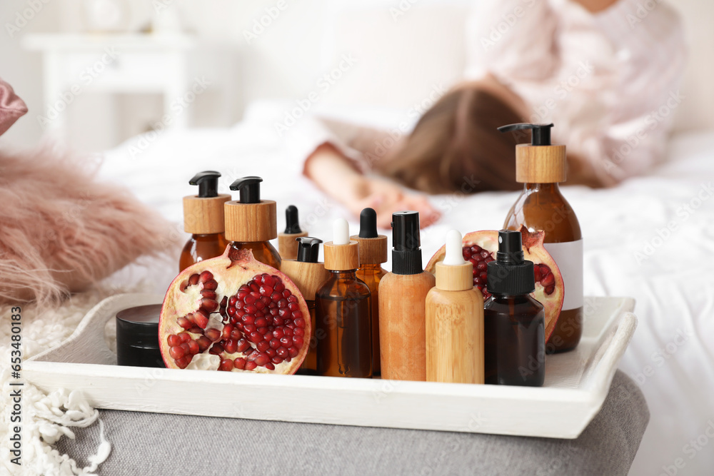 Tray with pomegranate and cosmetic products in bedroom, closeup