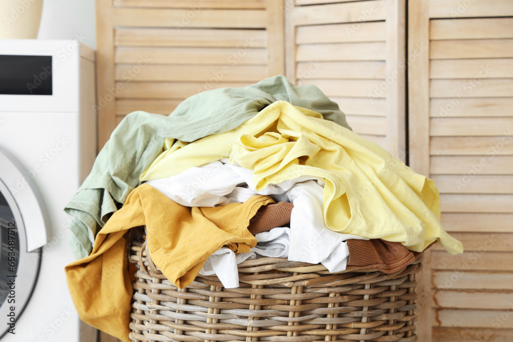 Wicker basket with dirty clothes in laundry room, closeup