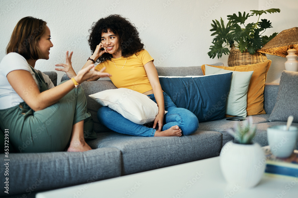 Women, friends and conversation in a home with gossip, discussion and happy in a living room. Couch, smile and people on a sofa with gossip or social together in a house lounge with speaking together