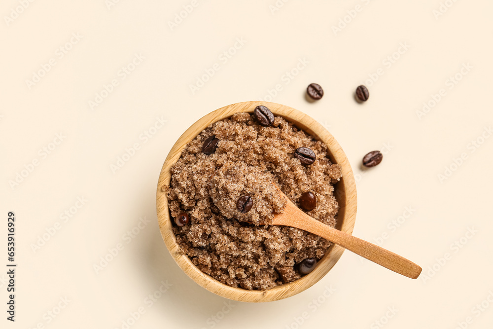 Bowl of body scrub and coffee beans on light background