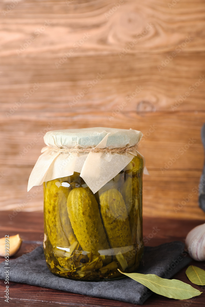 Jar with tasty canned cucumbers and spices on wooden table