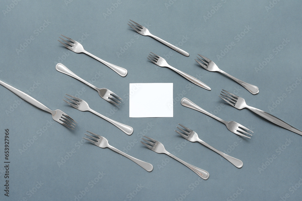 Composition with blank card and stainless steel forks on color background