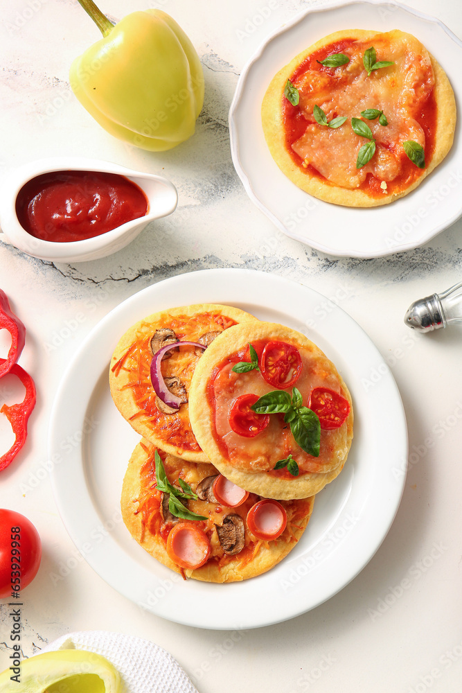 Plates with different tasty mini pizzas on white background