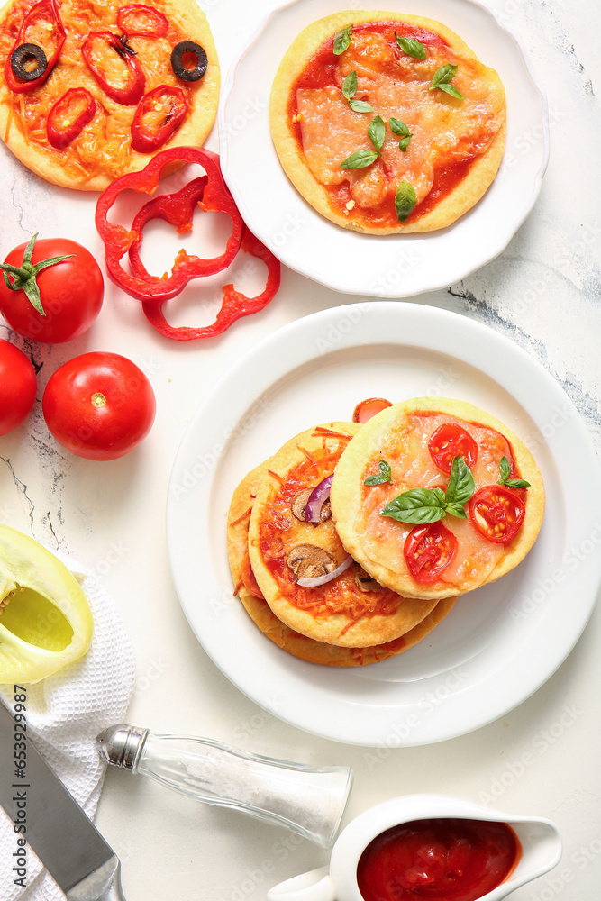 Plates with different tasty mini pizzas on white background