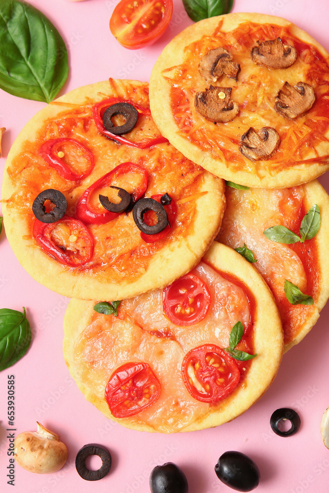 Different tasty mini pizzas and ingredients on pink background