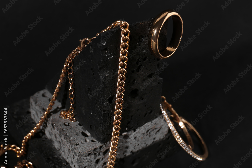 Decorative podium with beautiful jewellery on black background