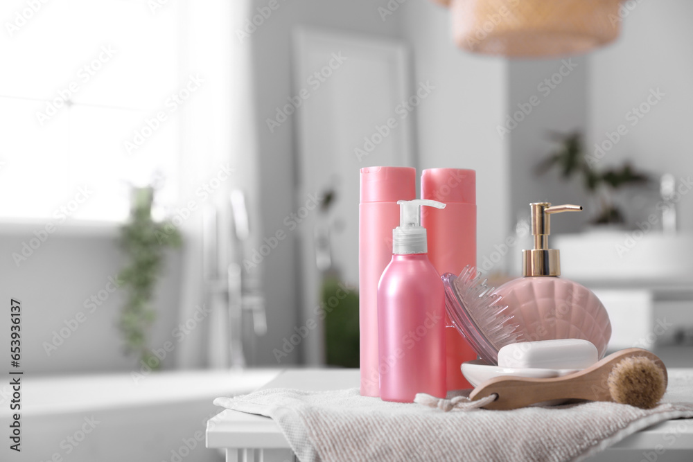 Brushes, soap dispenser and bath accessories on table in bathroom, closeup