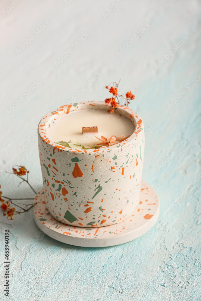 Holder with candle and flowers on blue background