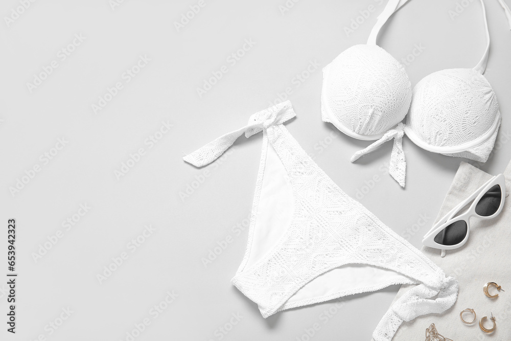 Stylish swimsuit, sunglasses, bag and accessories on light background