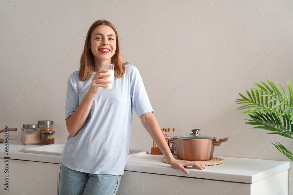 Young woman with glass of milk in kitchen