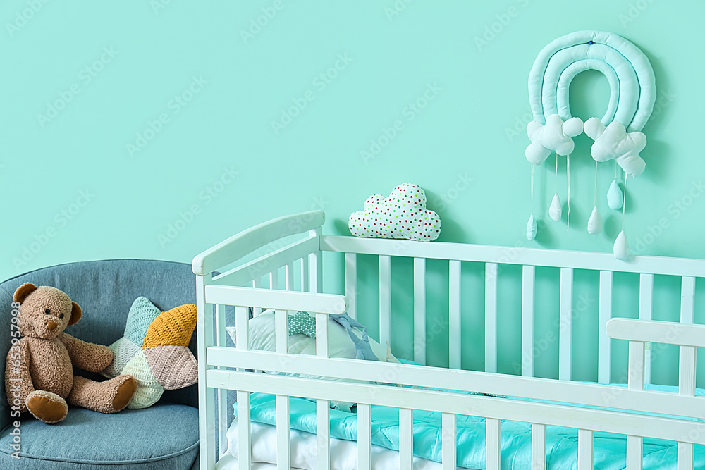 Interior of childrens room with crib near turquoise wall