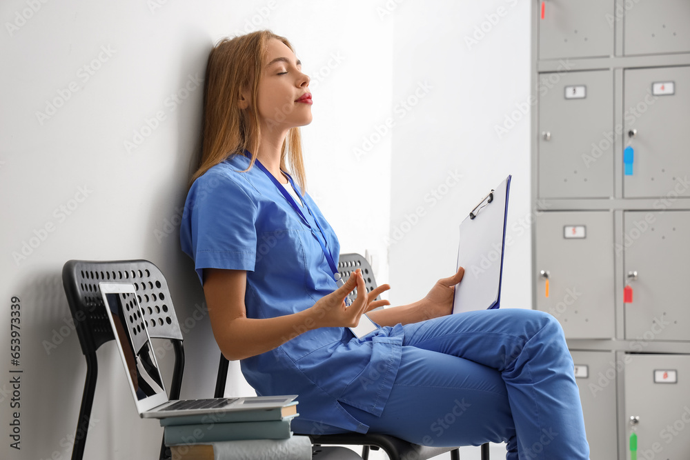 Female medical intern with clipboard meditating at university