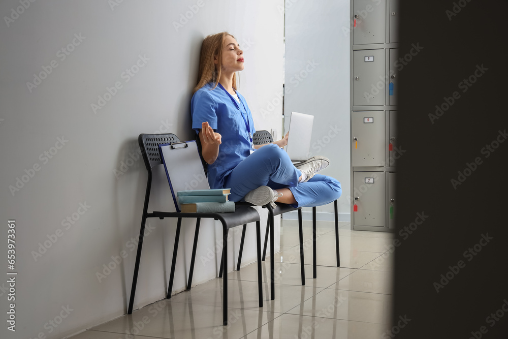 Female medical intern with laptop meditating at university