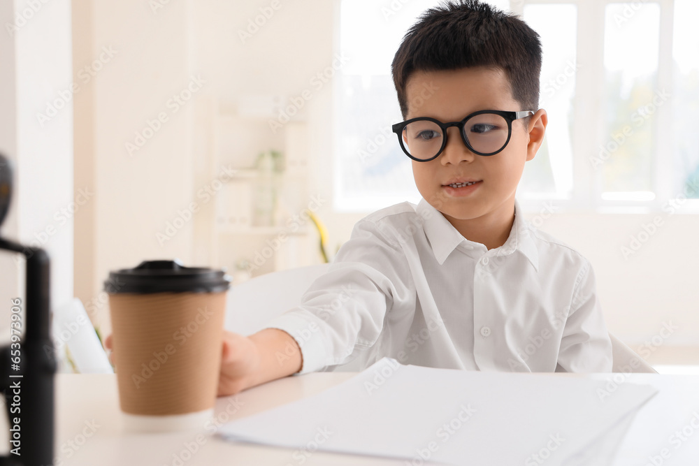 Cute little businessman with cup of coffee in office, closeup