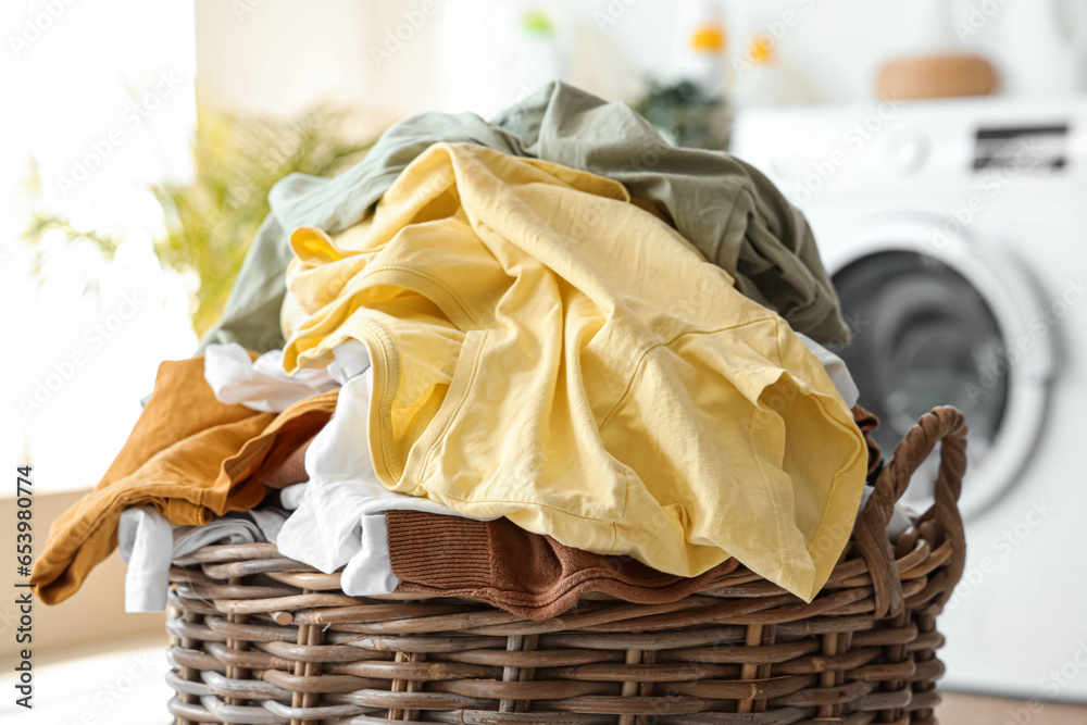 Wicker basket with dirty clothes in laundry room, closeup