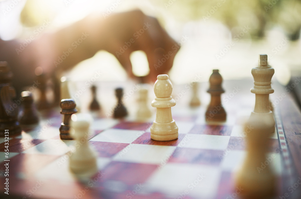 Closeup, chess and hand at park for challenge, strategy and moving silhouette in sunshine. Person, vintage board game and outdoor for contest, battle and problem solving with competition in summer