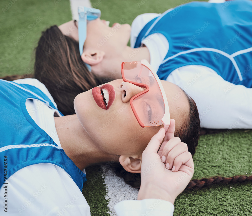 Style, sports and women hockey players relaxing on the grass field with cool, stylish and trendy outfit. Fashion, fitness and portrait of female athlete friends laying in stadium after game or match.