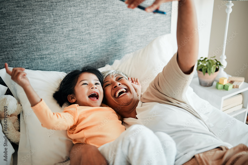 Selfie, grandmother and relax child on bed bonding, excited and love for happy family with care. Photography, technology and senior woman with little girl in bedroom on video call together in home.