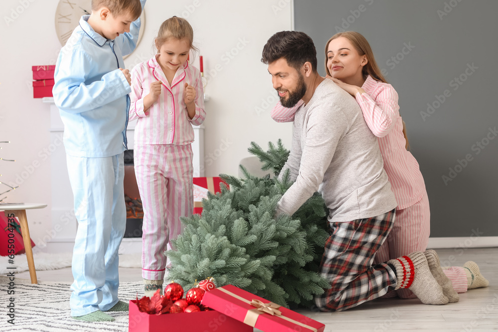 Happy parents and their little children with Christmas tree at home