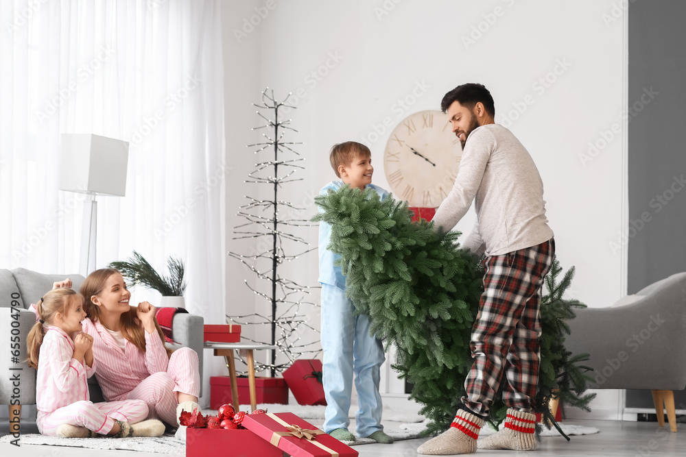 Happy parents and their little children with Christmas tree at home