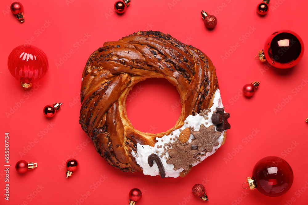 Composition with tasty Christmas pastry wreath and balls on red background