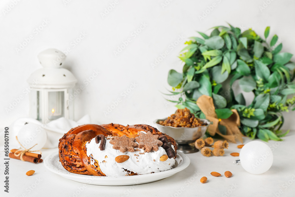 Plate with tasty Christmas pastry wreath and decorations on light background