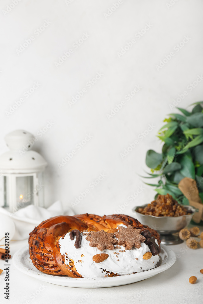 Plate with tasty Christmas pastry wreath and Kutya on light background