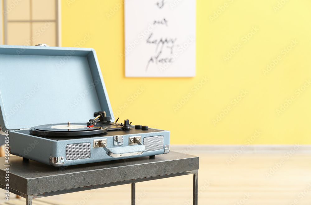 Record player with vinyl disk on table in room