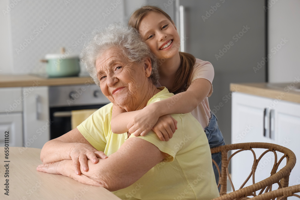 Little girl with her grandmother hugging in kitchen