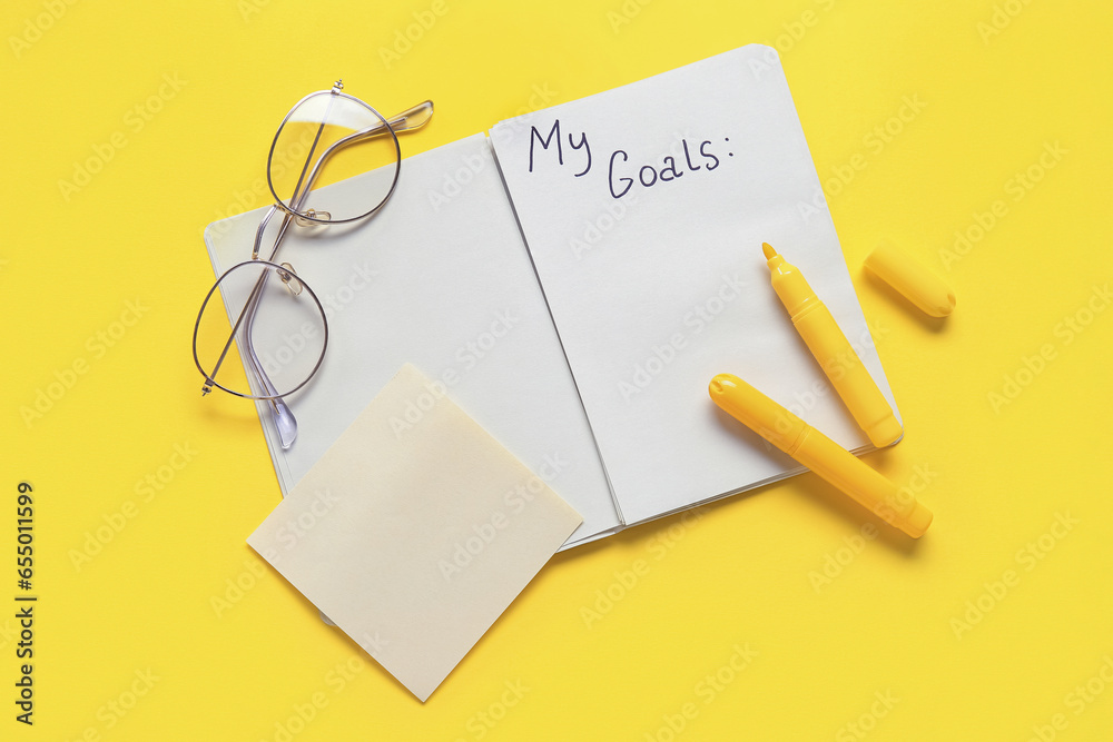 Notebook with empty to do list, markers and eyeglasses on yellow background. New year goals