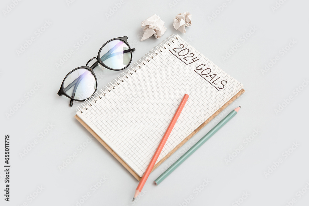 Notebook with empty to do list, eyeglasses and pencils on white background. New year goals